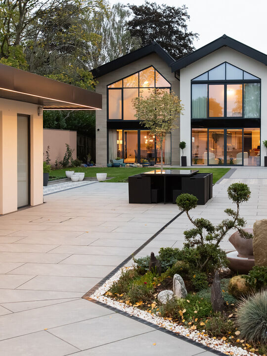 Luxury contemporary home with landscaped courtyard, large glazing and modern outdoor living space at dusk