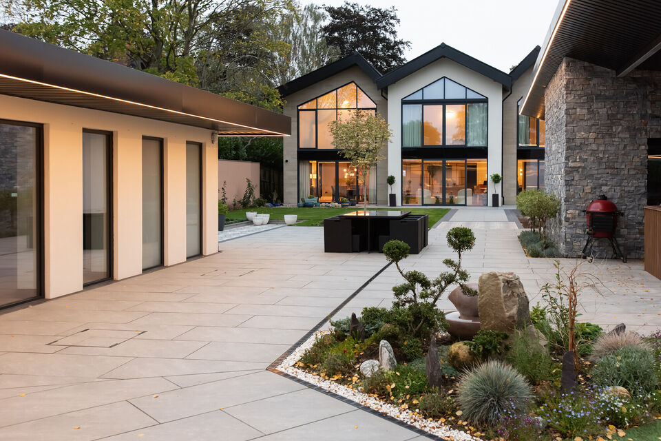 Luxury contemporary home with landscaped courtyard, large glazing and modern outdoor living space at dusk