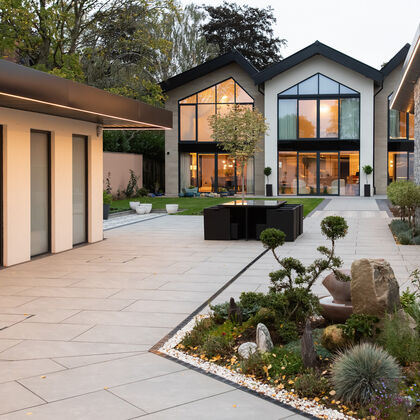 Luxury contemporary home with landscaped courtyard, large glazing and modern outdoor living space at dusk
