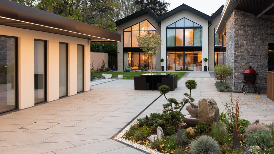 Luxury contemporary home with landscaped courtyard, large glazing and modern outdoor living space at dusk