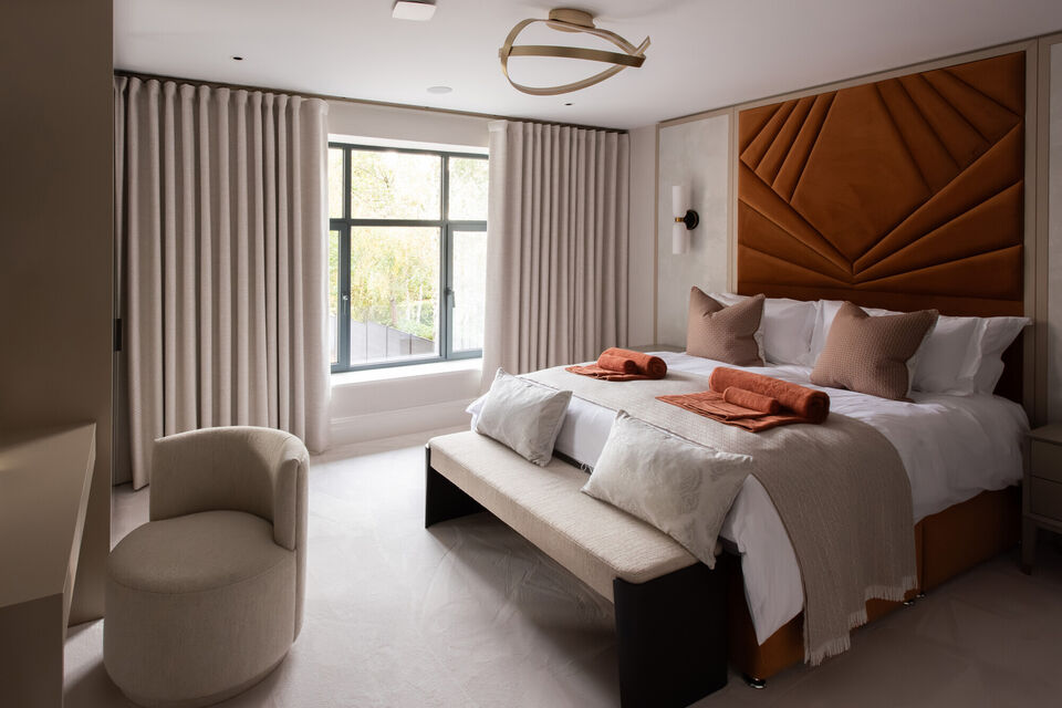 Luxury contemporary bedroom with bespoke upholstered headboard, soft neutral finishes and large window