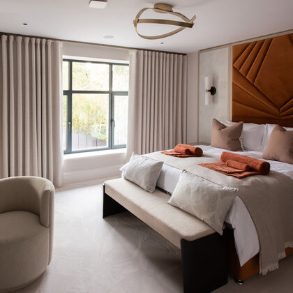 Luxury contemporary bedroom with bespoke upholstered headboard, soft neutral finishes and large window