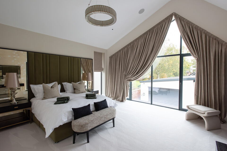 Luxury contemporary bedroom with vaulted ceiling, bespoke headboard and full-height glazing