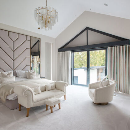 Luxury principal bedroom suite with vaulted ceiling, bespoke wall panelling and full-height glazing