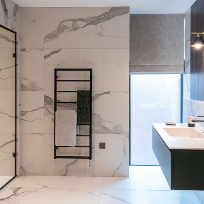 Luxury contemporary bathroom with large-format marble tiles, walk-in shower and floating vanity, black furniture