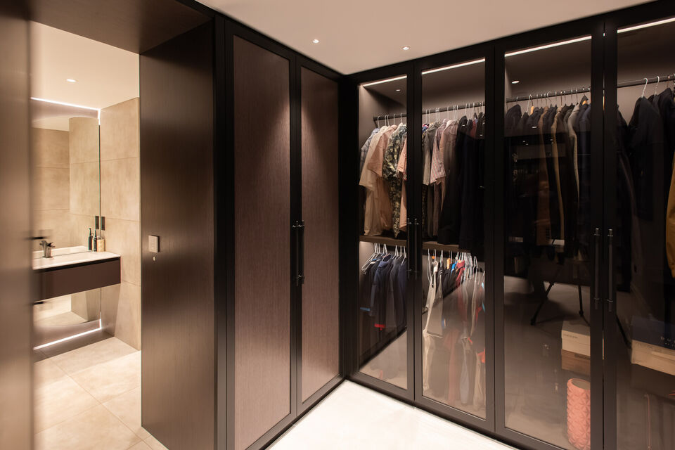 Luxury walk-in wardrobe with bespoke joinery, glass-fronted wardrobes and integrated lighting