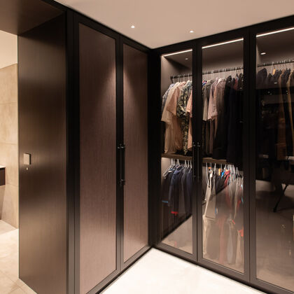Luxury walk-in wardrobe with bespoke joinery, glass-fronted wardrobes and integrated lighting