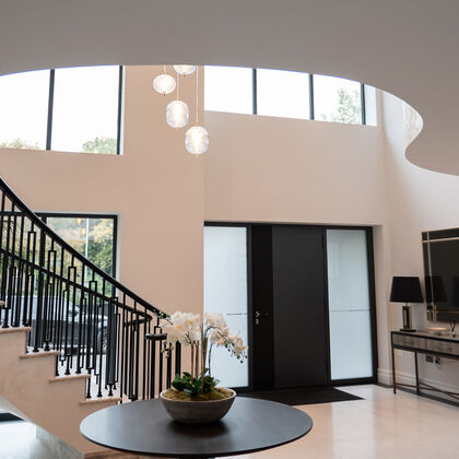 Luxury double-height entrance hall with curved staircase, feature glazing and pendant lighting