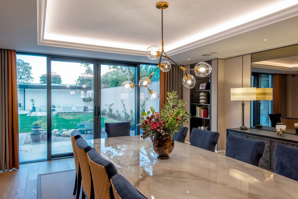 Luxury contemporary dining room with marble dining table, statement pendant lighting and sliding glass doors