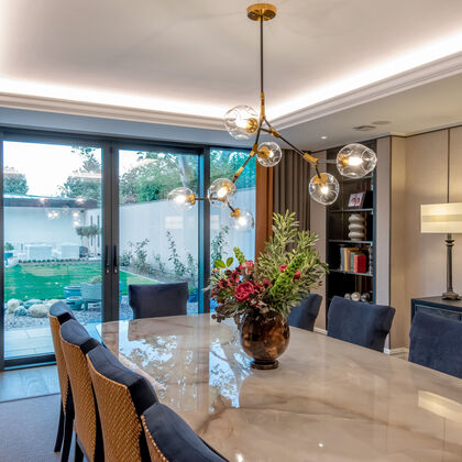 Luxury contemporary dining room with marble dining table, statement pendant lighting and sliding glass doors