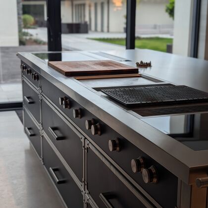 Bespoke kitchen island with professional-grade cooking suite and stainless steel worktop