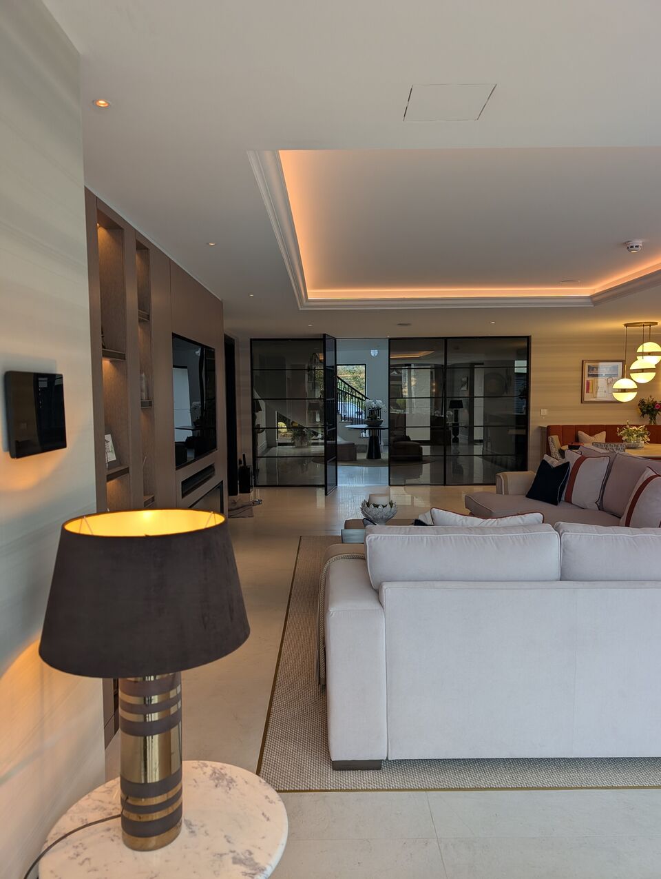 Luxury open-plan living room with coffered ceiling, integrated lighting and glass partition doors