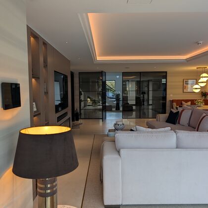 Luxury open-plan living room with coffered ceiling, integrated lighting and glass partition doors