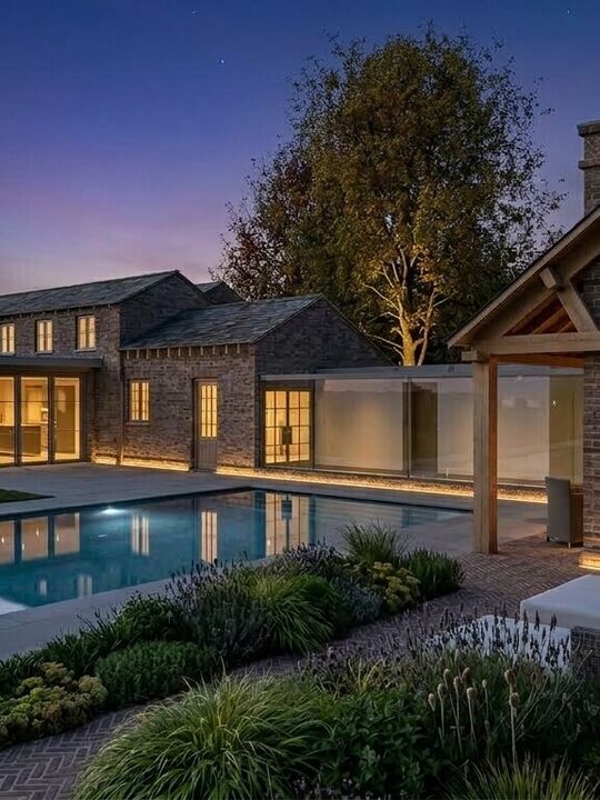 Poolside view of Luxury extension to a Cheshire cottage featuring panoramic floor-to-ceiling glass link, outdoor swimming pool and outdoor fireplace.