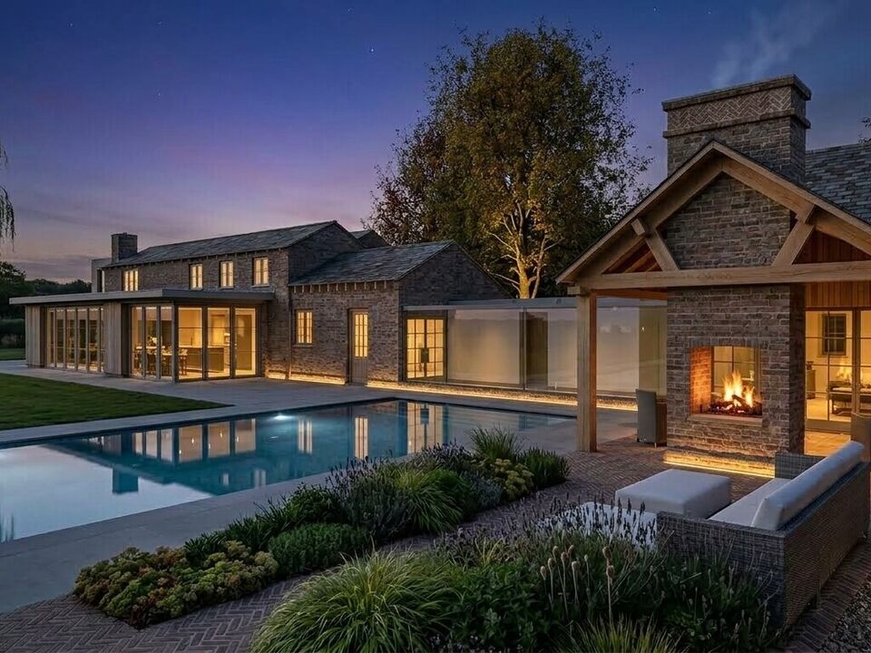 Poolside view of Luxury extension to a Cheshire cottage featuring panoramic floor-to-ceiling glass link, outdoor swimming pool and outdoor fireplace.